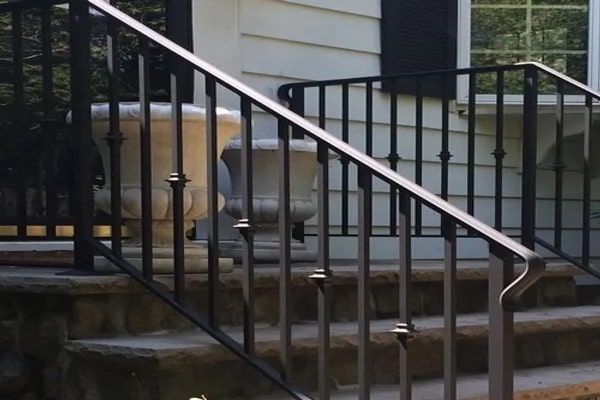 Black metal handrail on stone steps leading to a house.