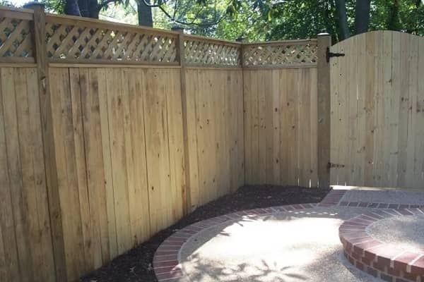 Wooden fence with lattice top and gate in a yard.