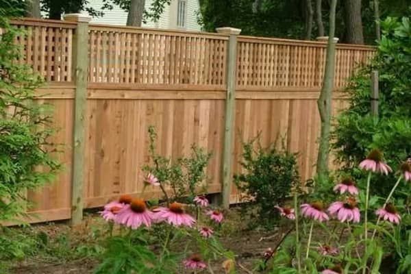 Wooden fence with lattice top, flowers in front.
