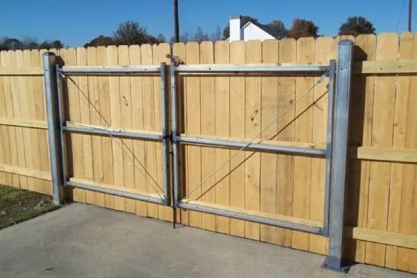 Wooden fence with metal-framed double gate. The gate is closed.