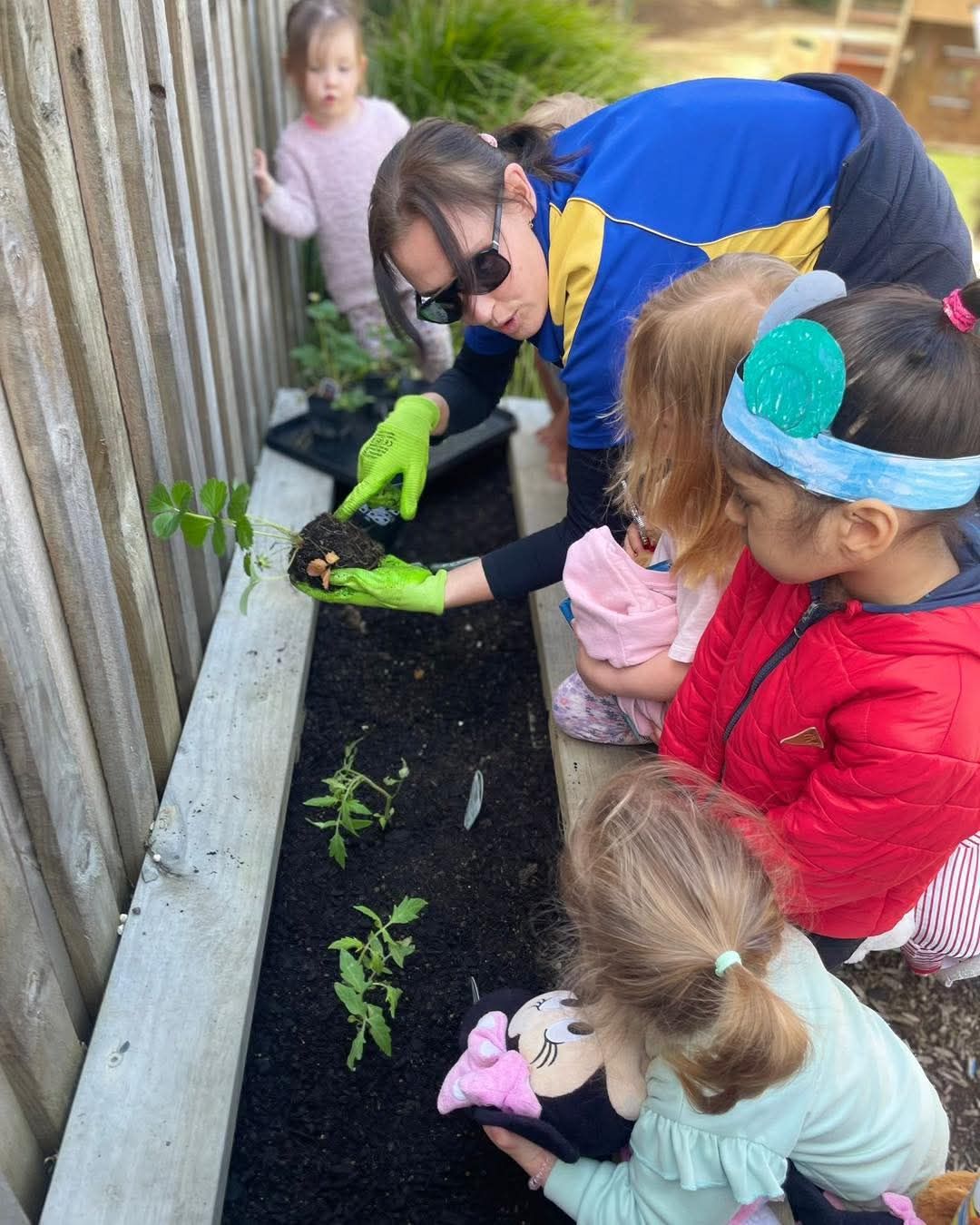 A group of children are planting plants in a garden.