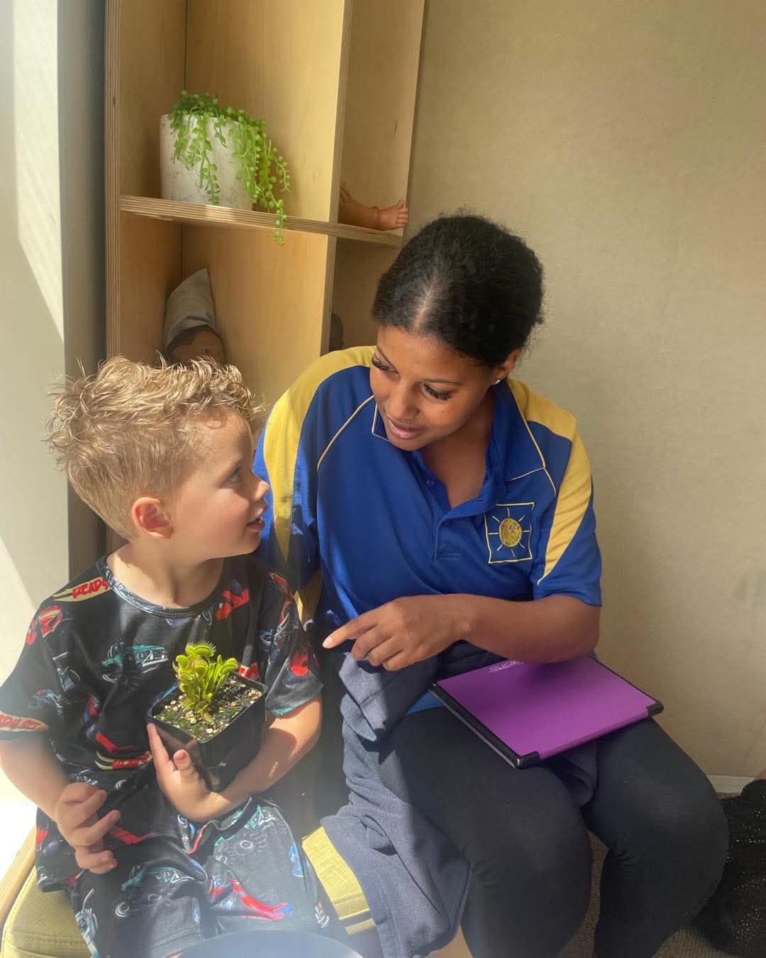 A woman is sitting next to a young boy holding a plant.