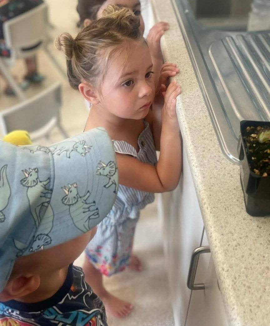 A boy and a girl are looking at something on a counter.