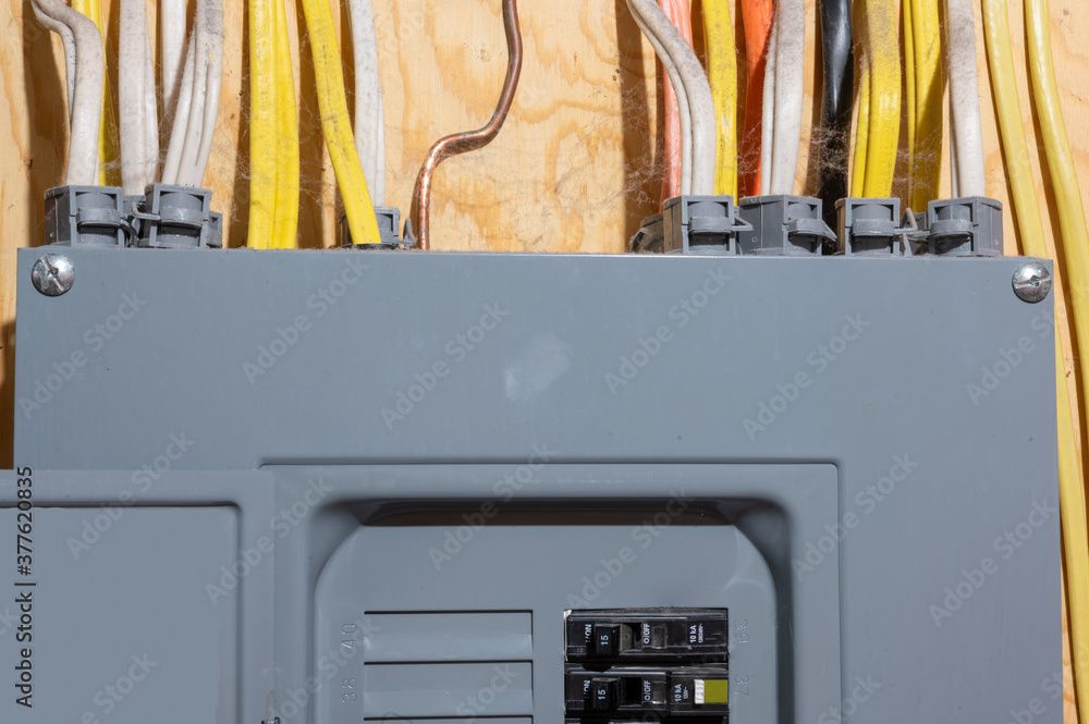 Gray electrical panel with attached wires against a wood background.