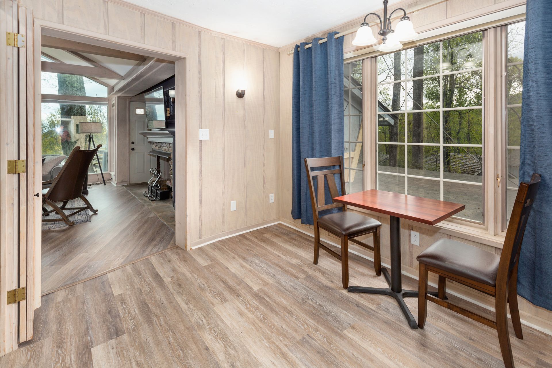 A room with a table and chairs in front of a window.