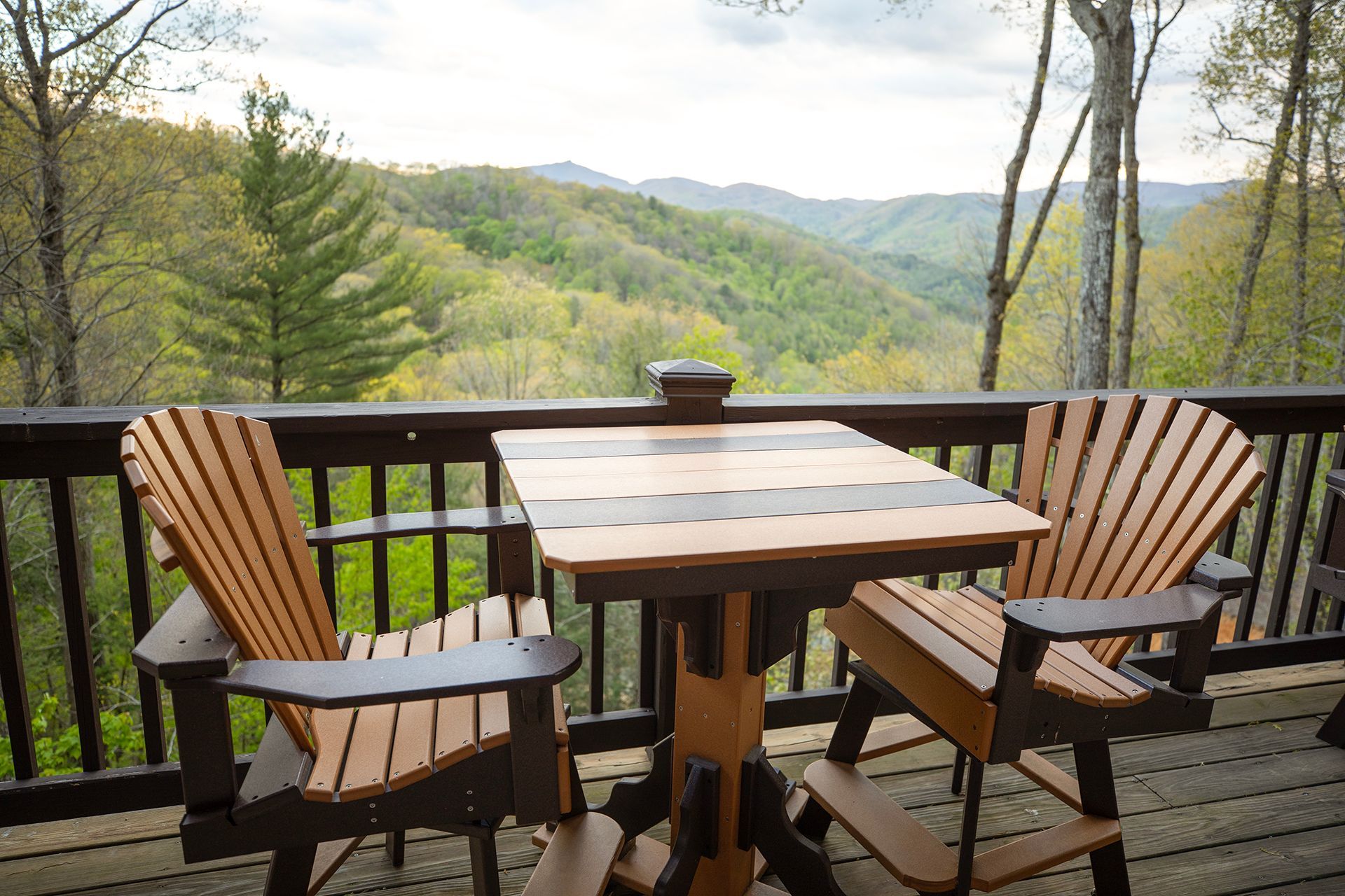 A wooden table and chairs on a deck overlooking a forest.