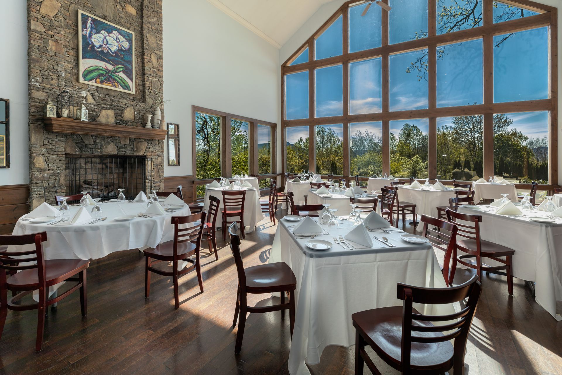 A large dining room with tables and chairs and a fireplace.