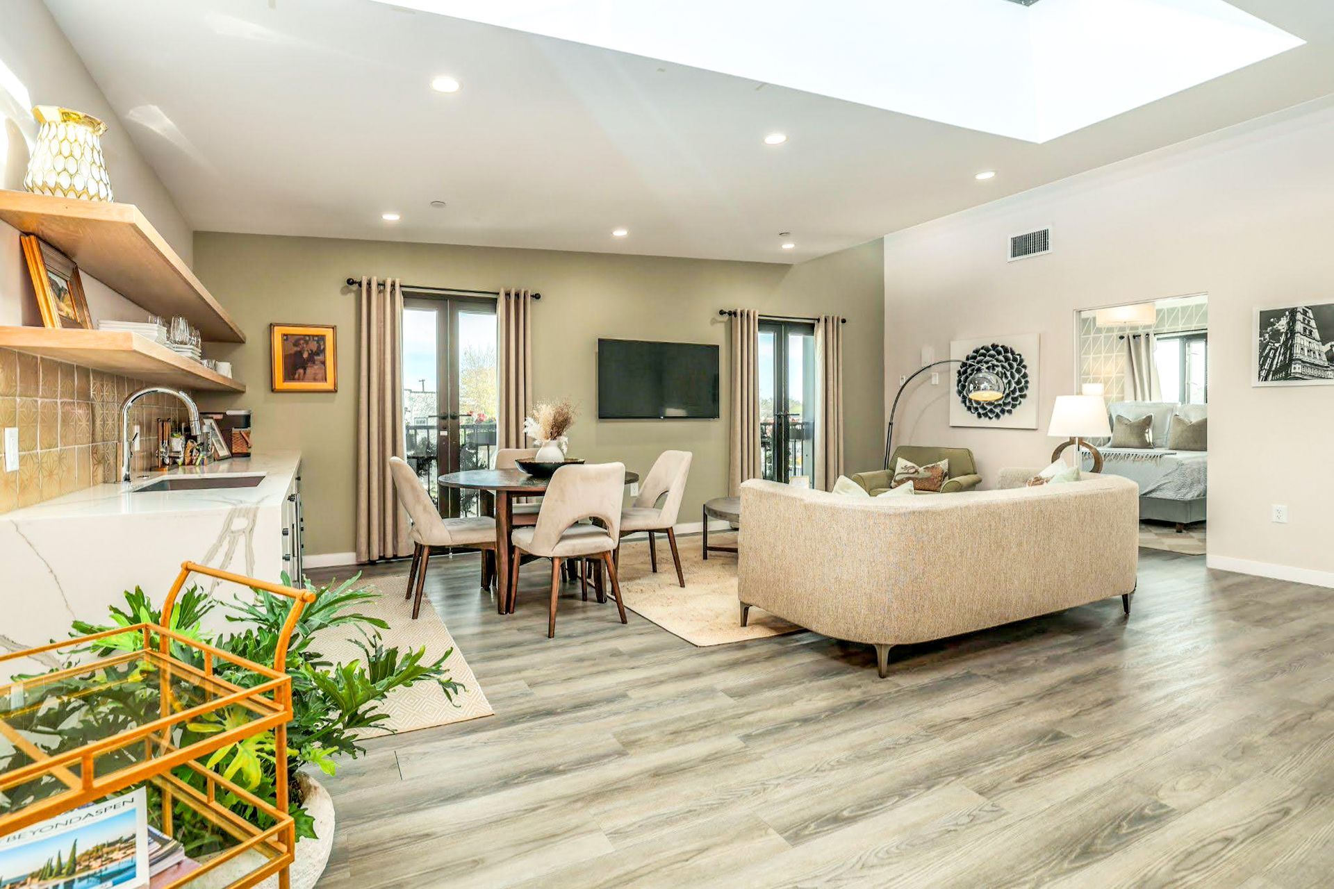 A living room with a couch , table , chairs and a flat screen tv.