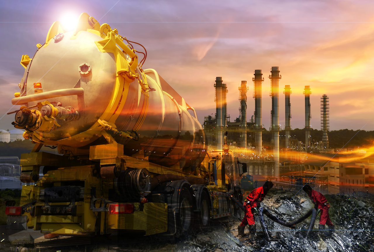 A vacuum truck is cleaning a dirty pipe in front of a factory.