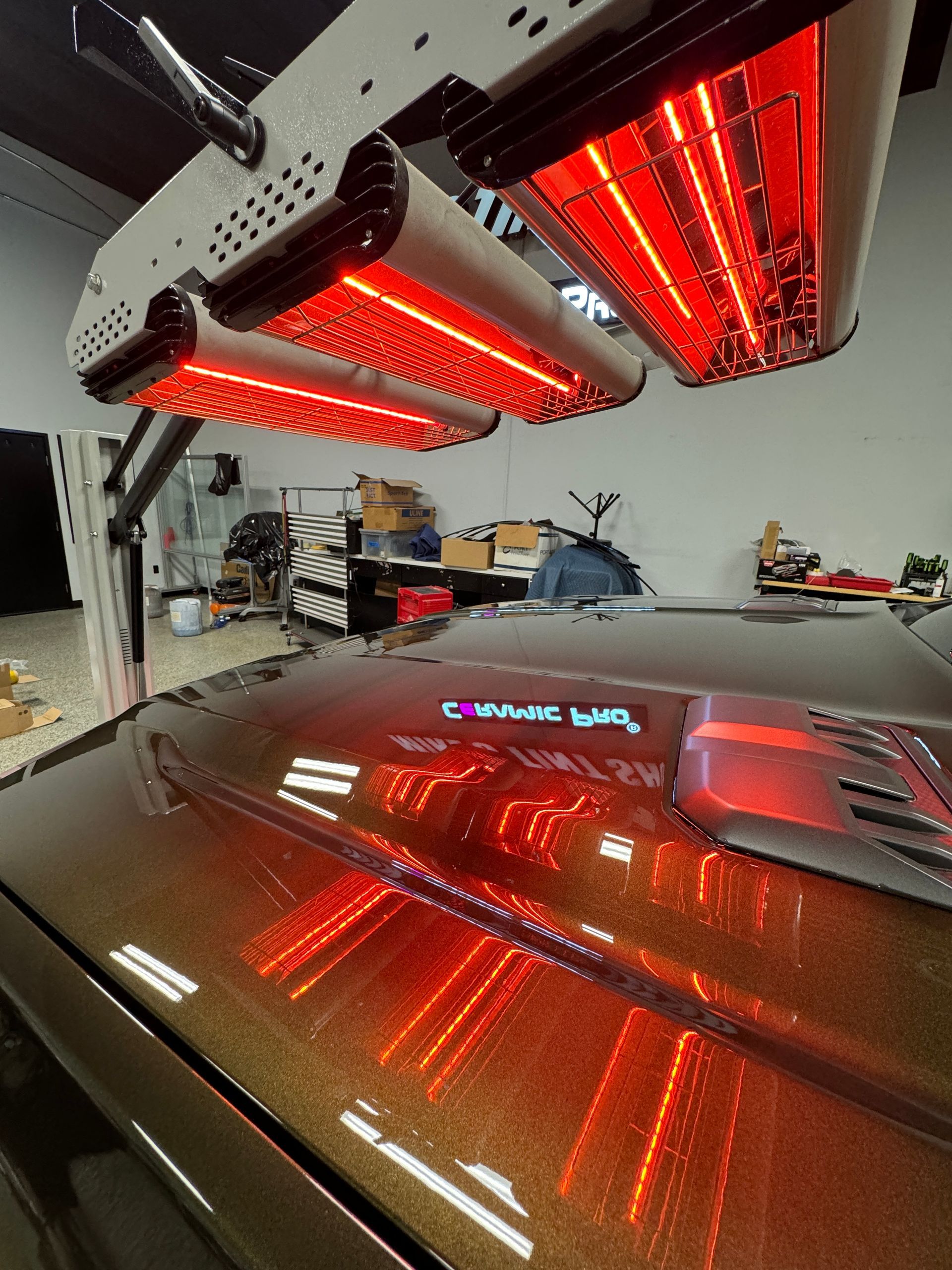 A car is sitting under a red light in a garage.