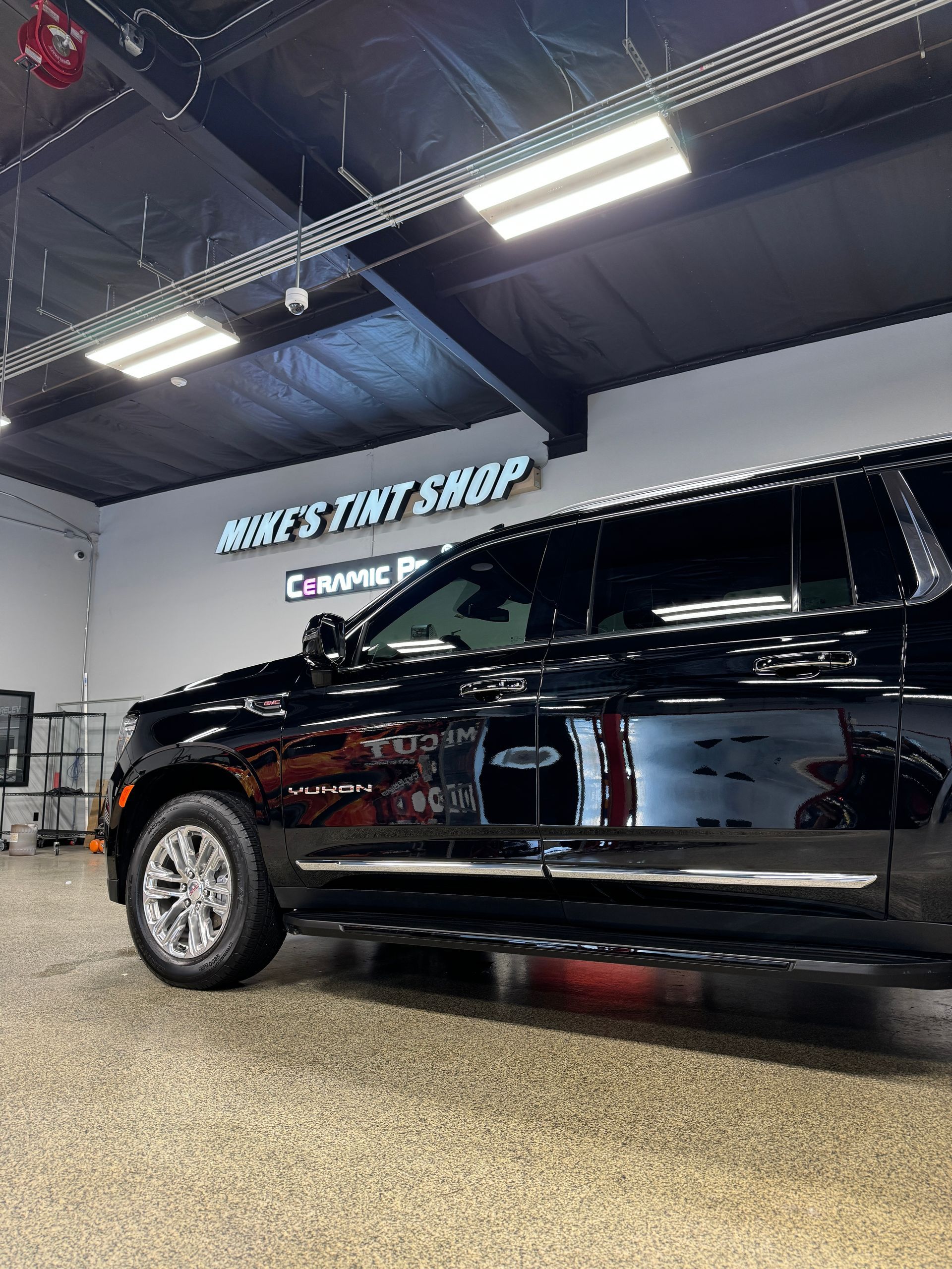 Person applying tint to a car window with a tool, outdoors.