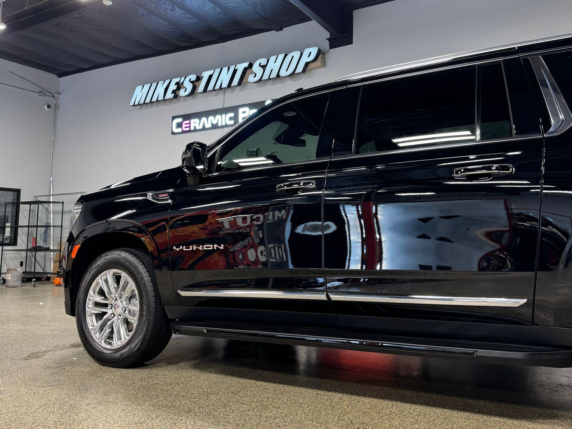 Black Yukon SUV with tinted windows, parked inside Mike's Tint Shop.