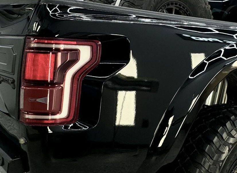 Black Ford truck tail light, red light, white outline, black paint, honeycomb fender.