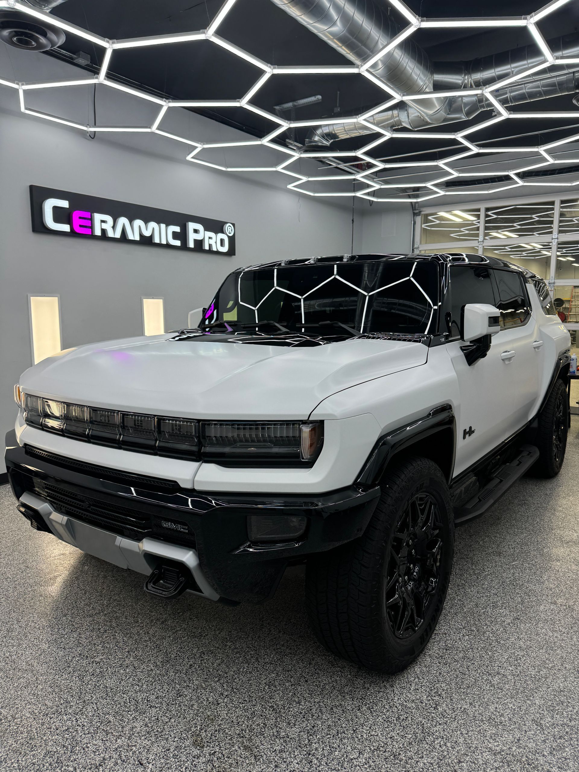 A black lamborghini aventador is parked in a garage next to a rack of tires.