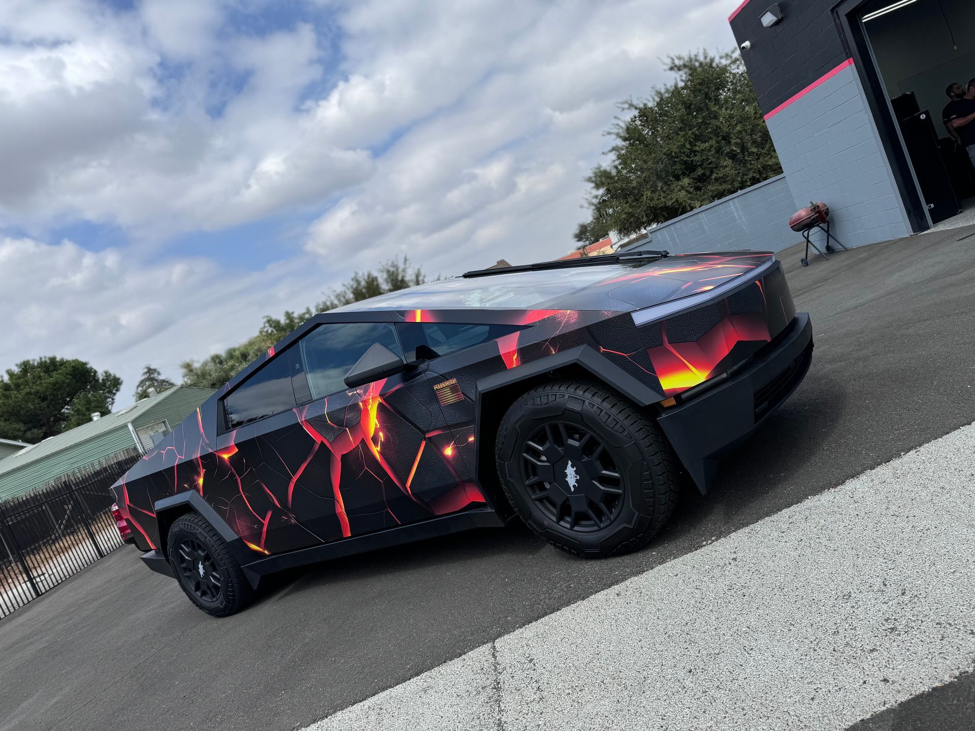 A tesla cybertruck is parked in the grass in front of a building.