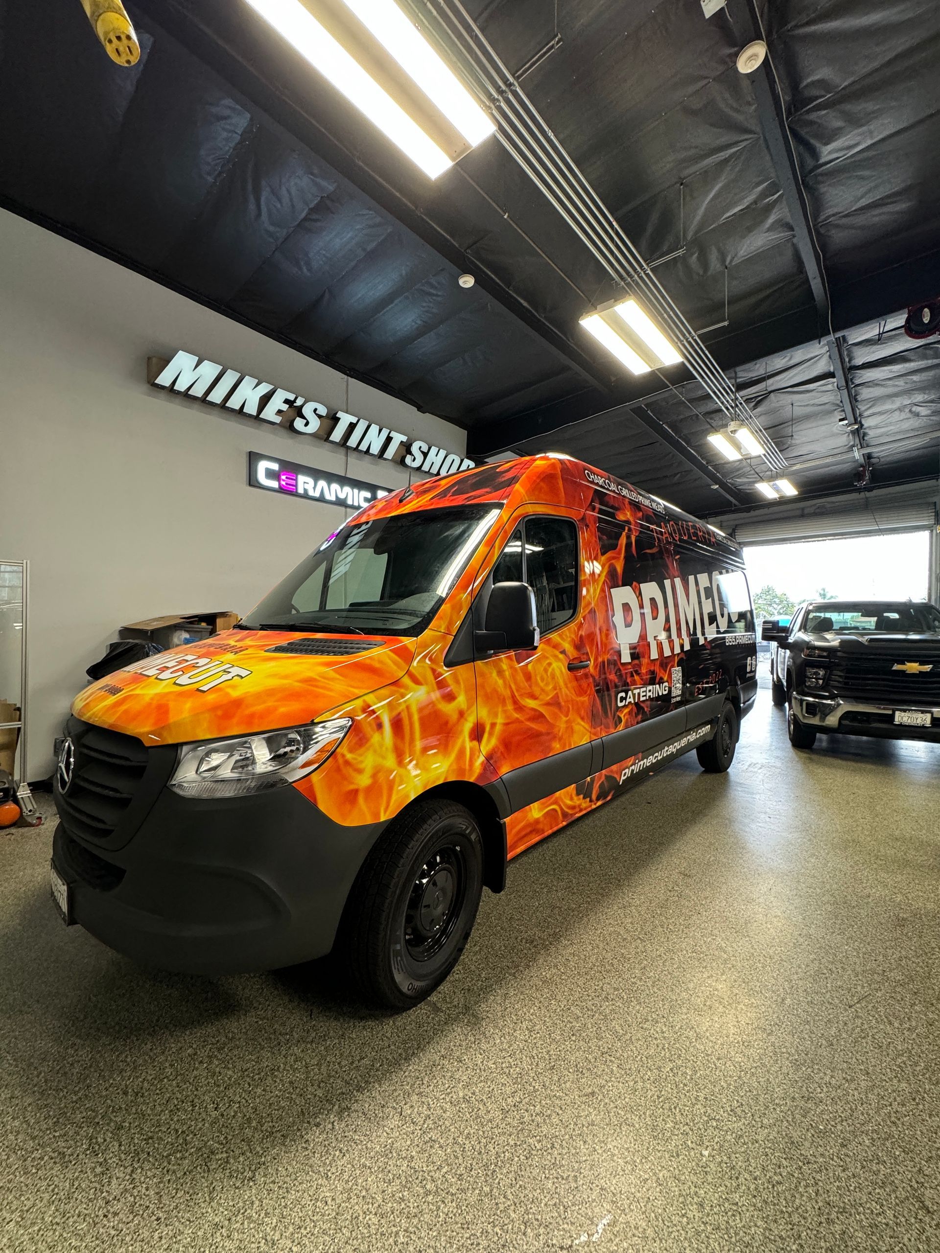 A van is wrapped in flames and is parked in a garage.