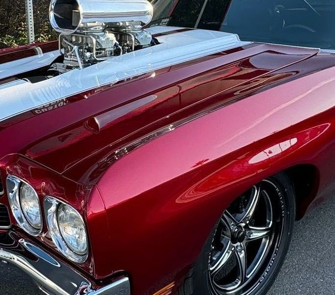 Red classic car with silver trim and engine, chrome wheels.