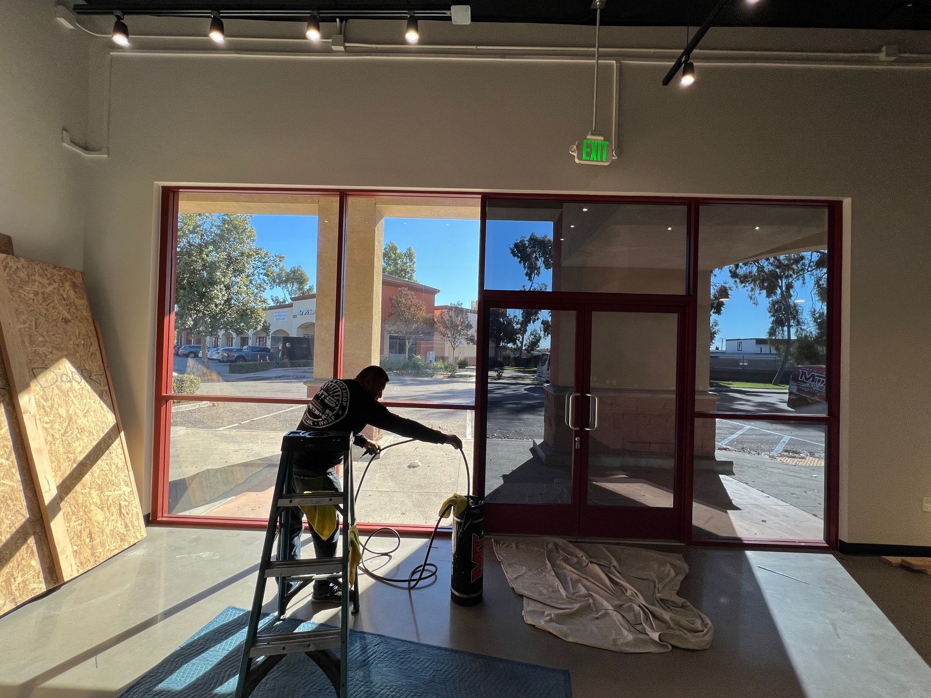 A man is standing on a ladder in front of a window.
