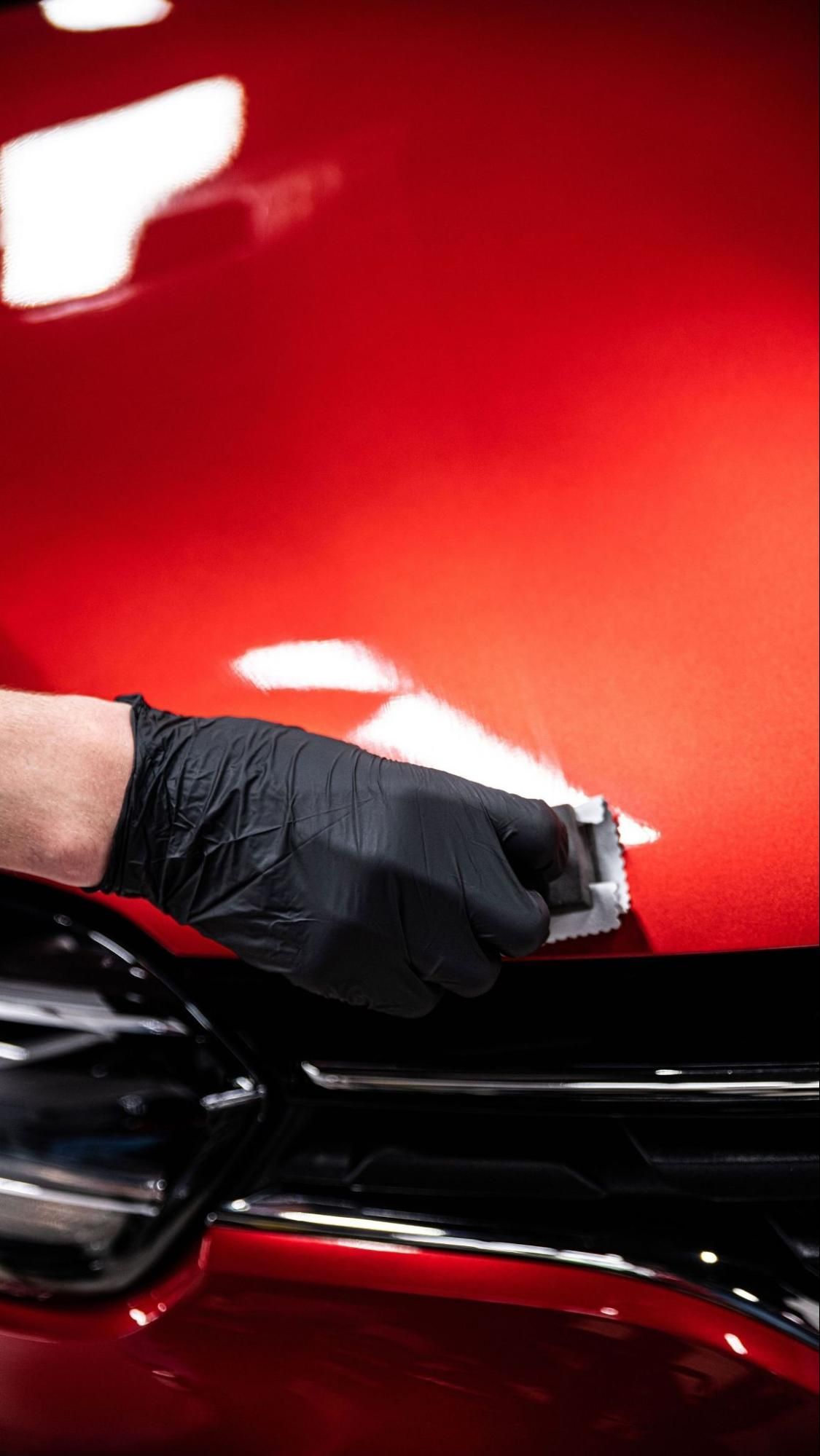 Person applying tinted film to a car window.