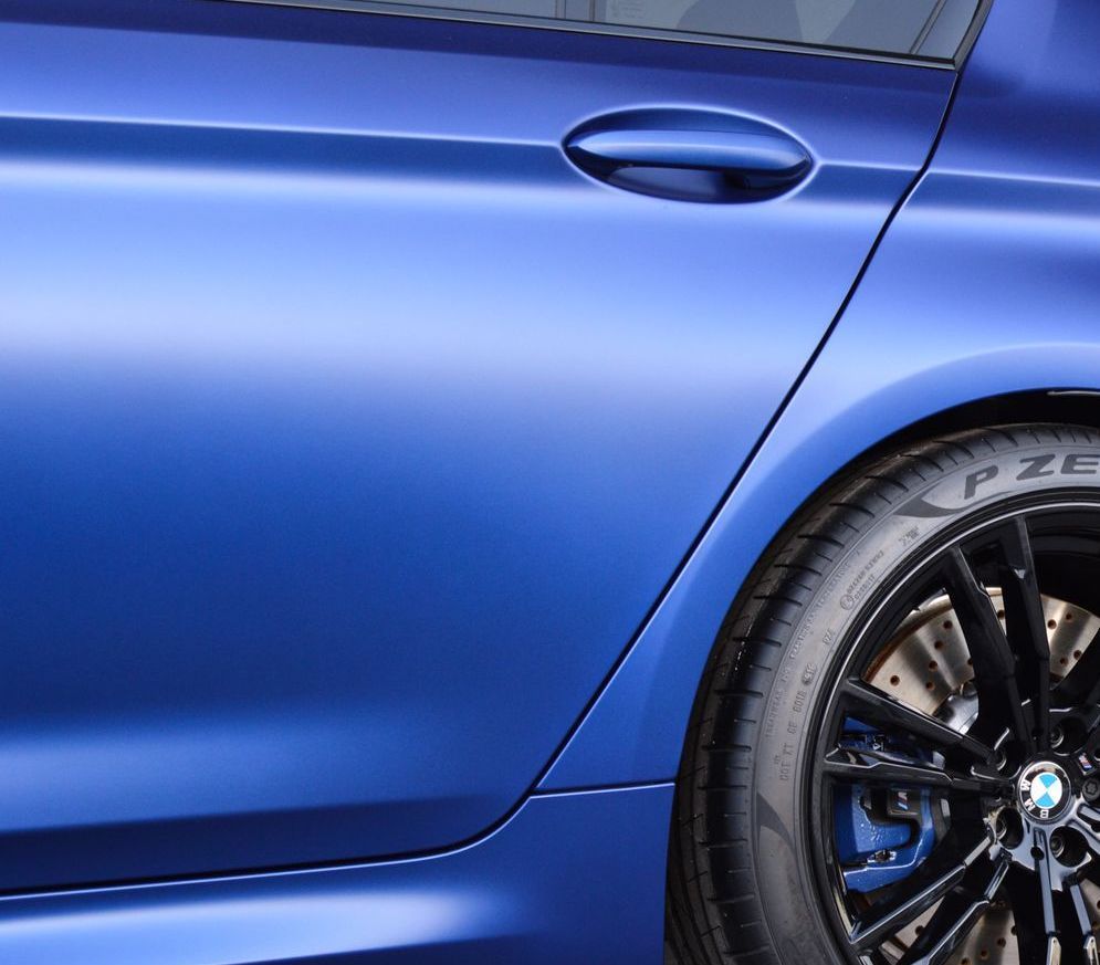 Blue car door with black wheel and tire;