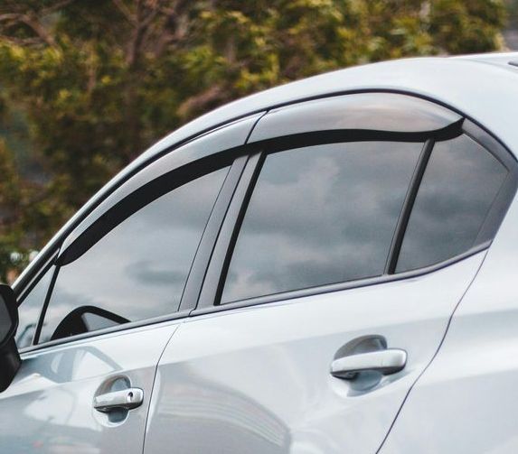 Silver car with tinted windows, a rain guard, and a dark cloudy sky in the background.