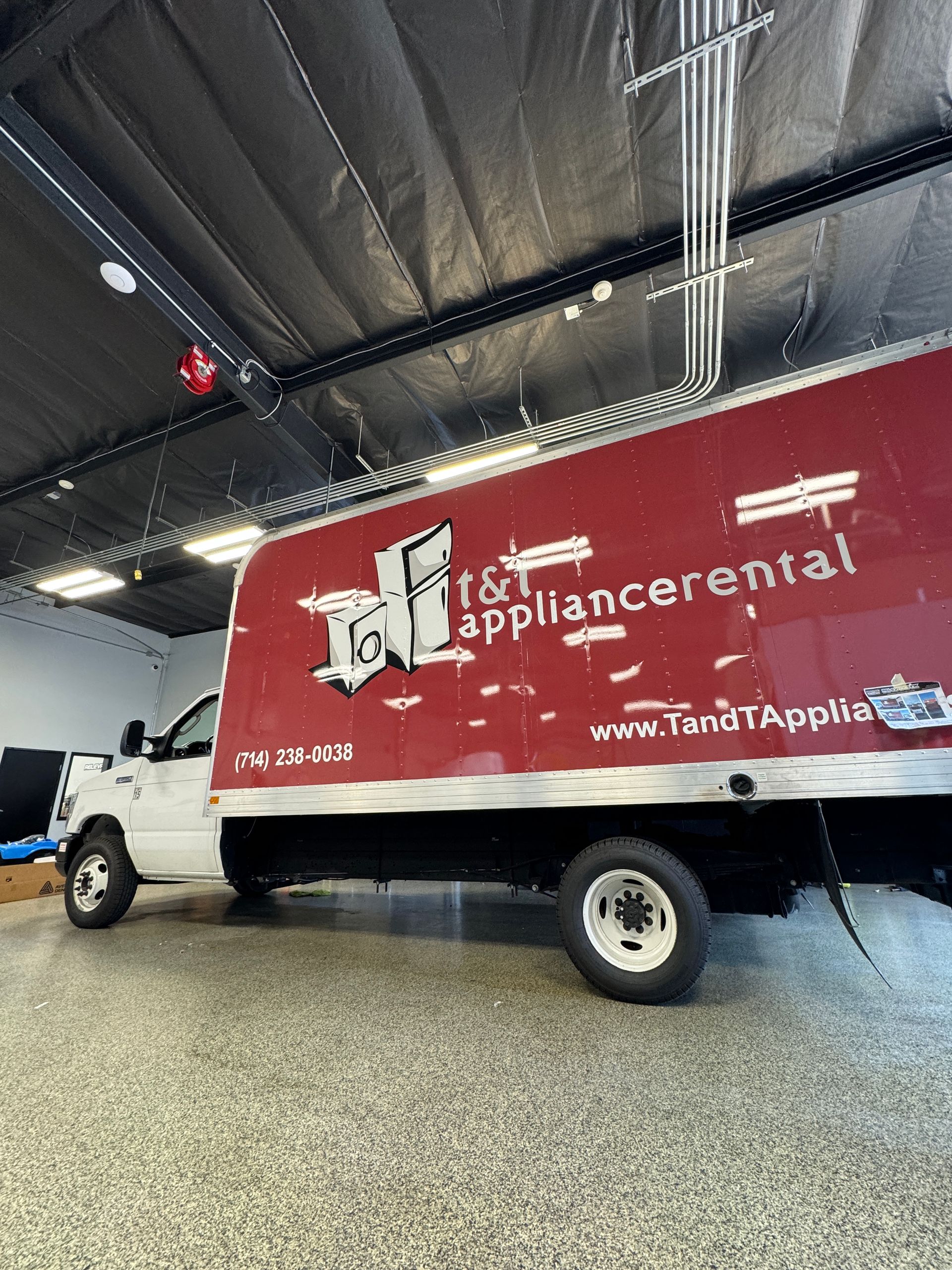 A red appliance central truck is parked in a garage.
