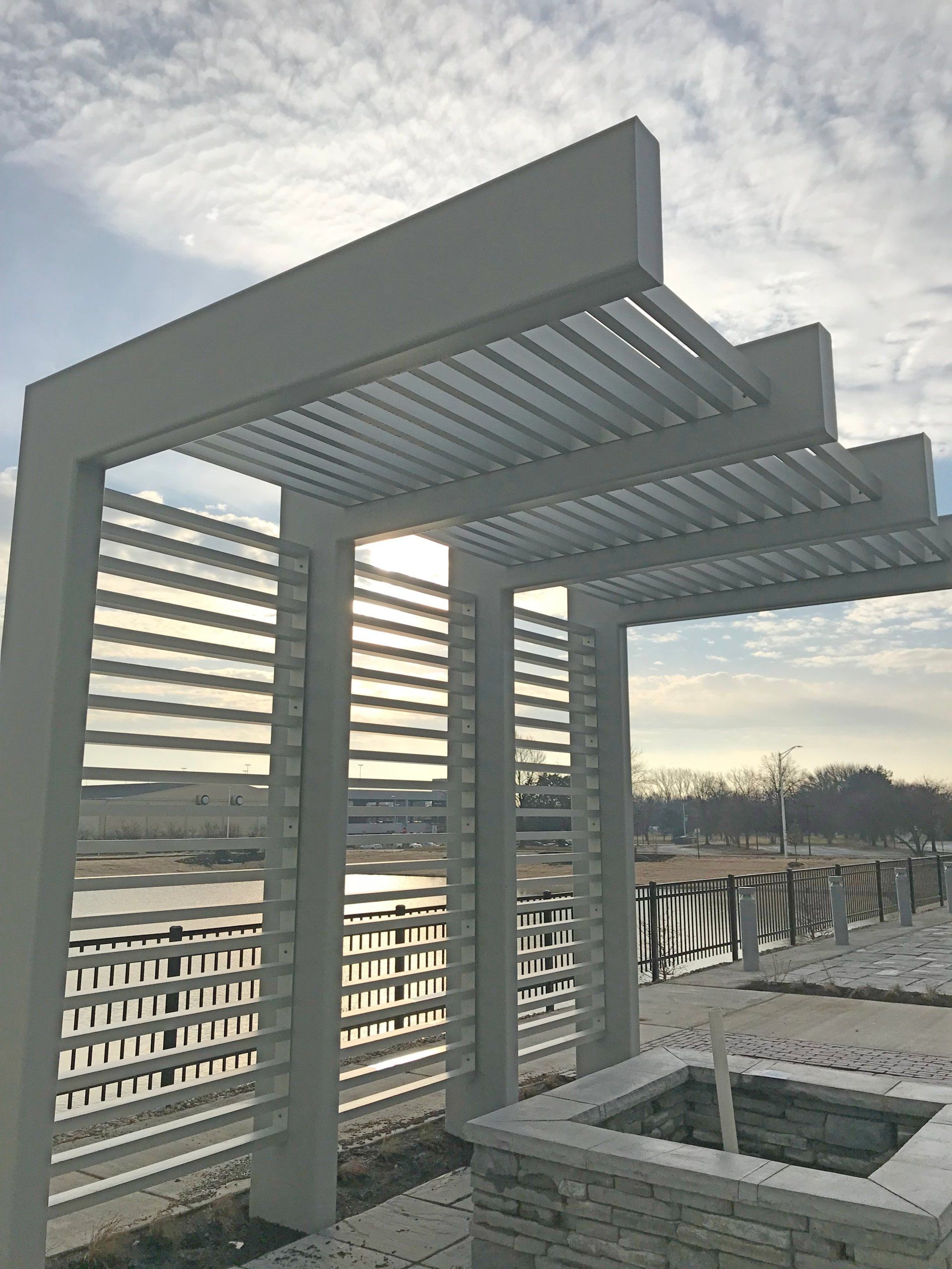 A white pergola with a fountain underneath it