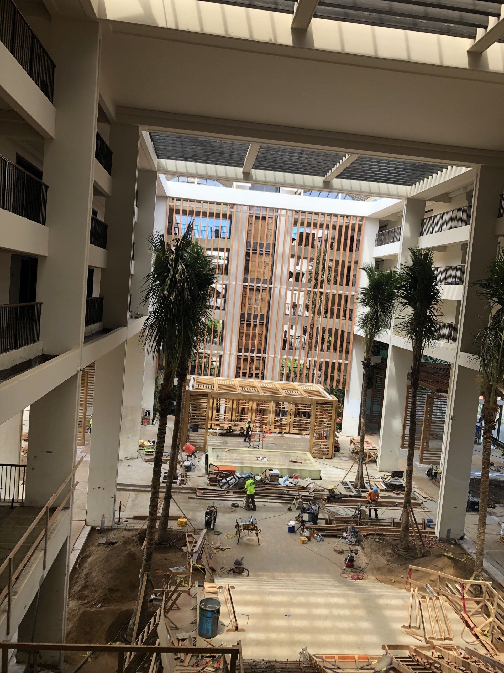 A large building under construction with palm trees in the middle