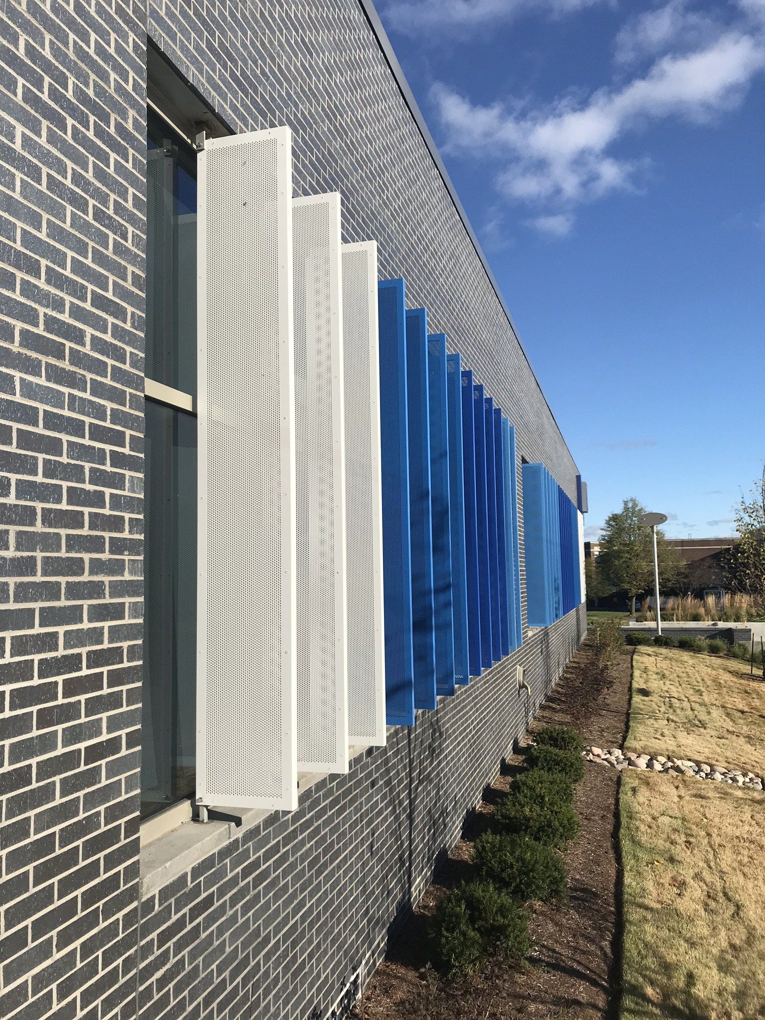 A brick building with blue and white shutters on the windows