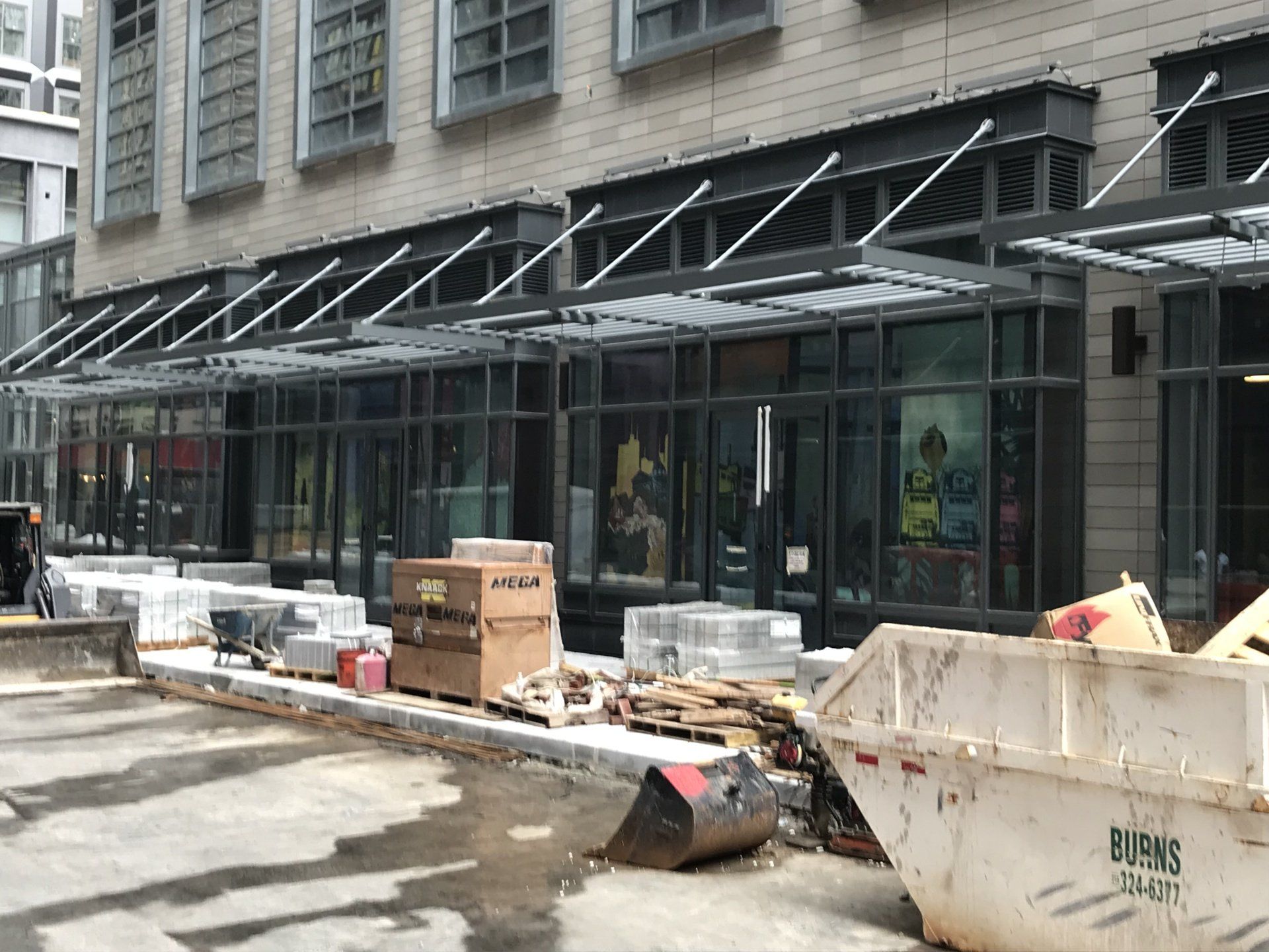 A large building under construction with a large white dumpster in front of it.