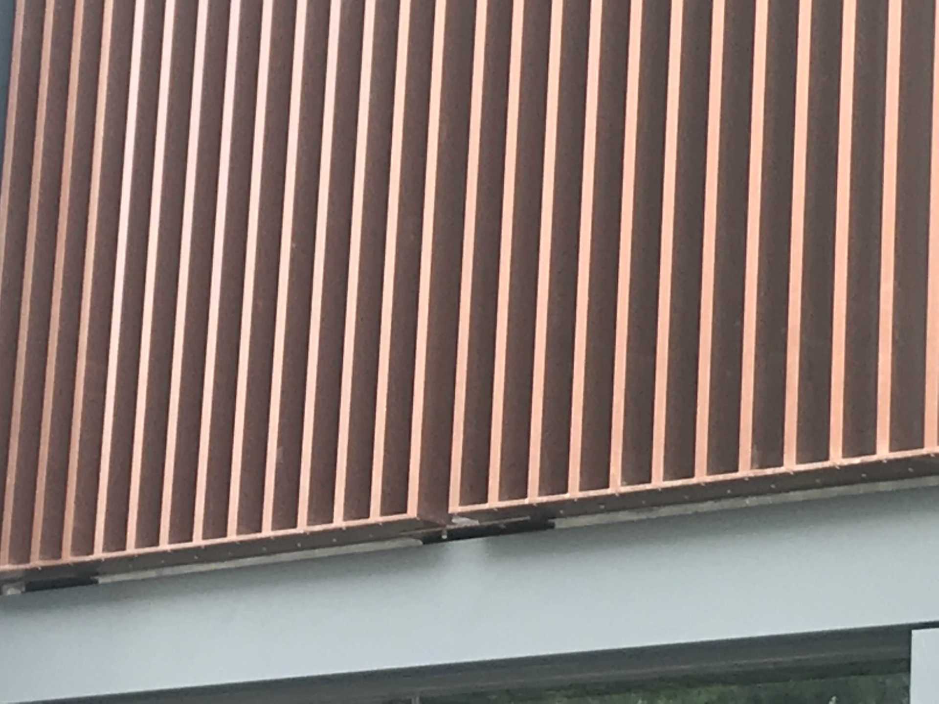 A close up of a copper fence on the side of a building.