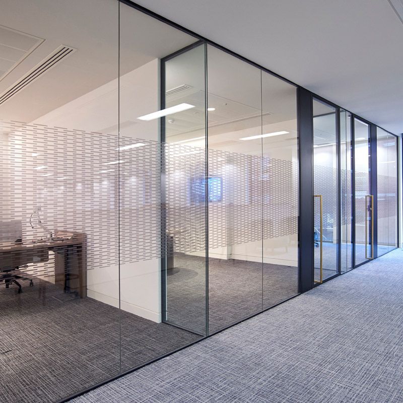 A hallway with glass walls and a desk in the middle of it.