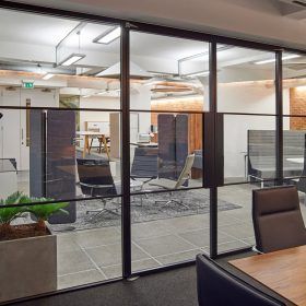 A conference room with a table and chairs and a glass wall.