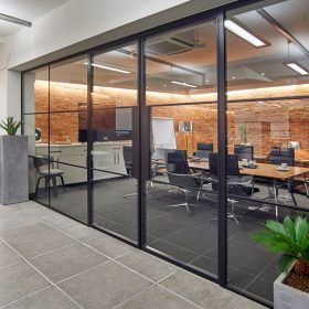 A conference room with a lot of glass doors and tables and chairs.