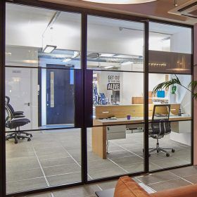 A room with a lot of windows and a desk and chairs in it.