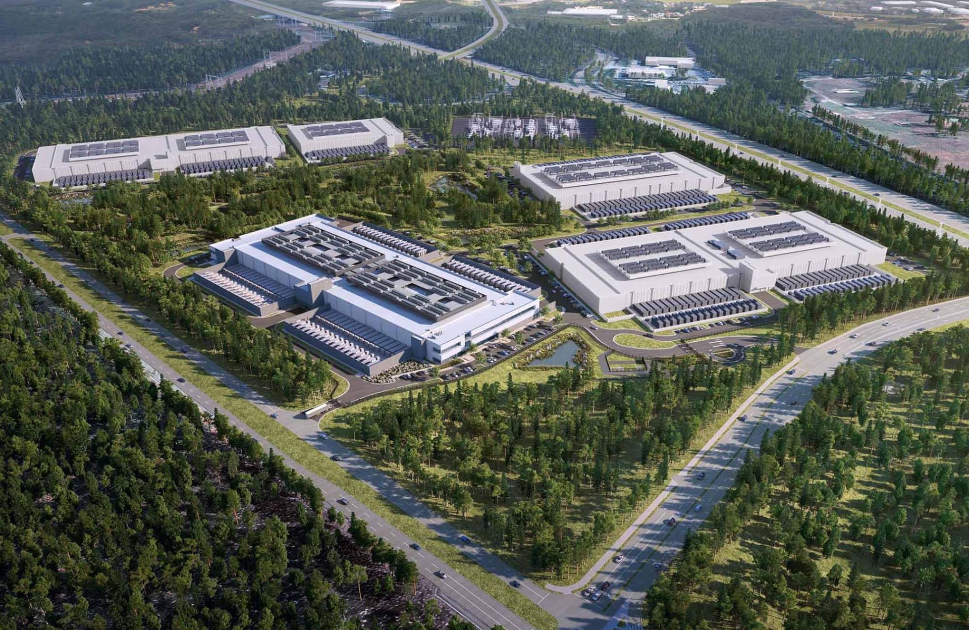 An aerial view of a large warehouse surrounded by trees and a highway.