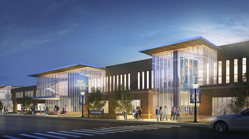 A car is parked in front of a large building at night.