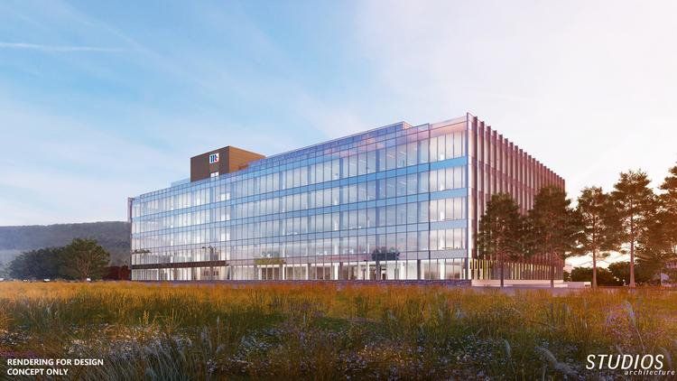 A large building with a lot of windows is sitting in the middle of a field.