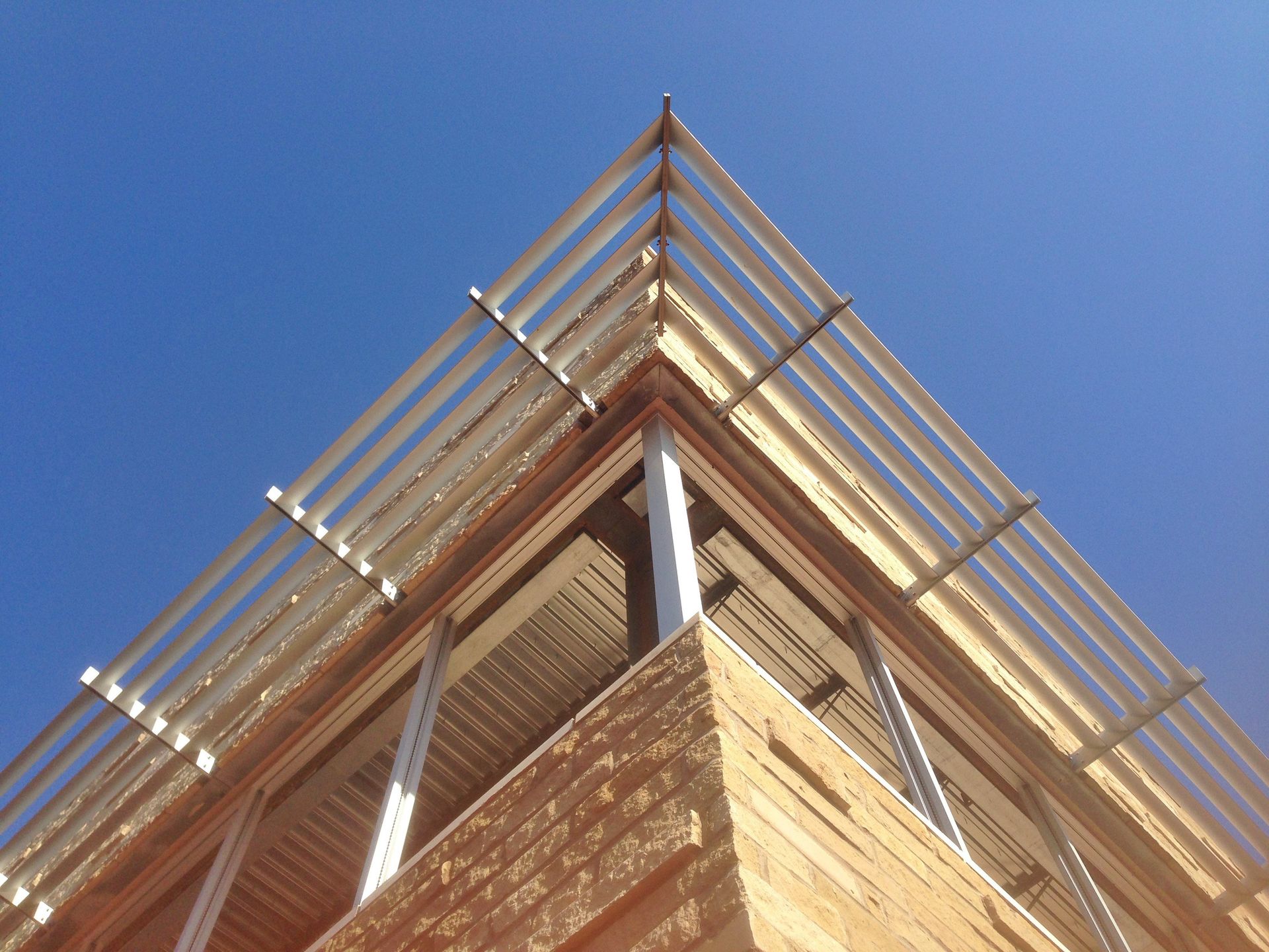 Looking up at the corner of a building with a blue sky in the background