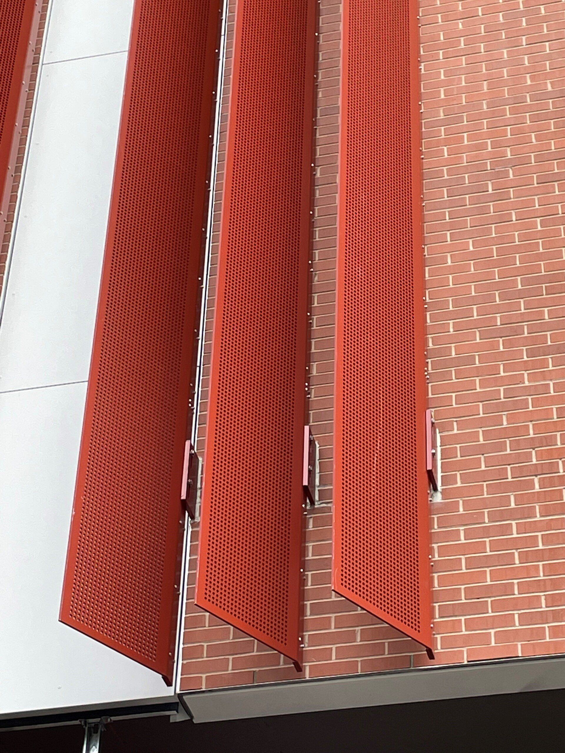 A brick building with red shutters on the side of it.