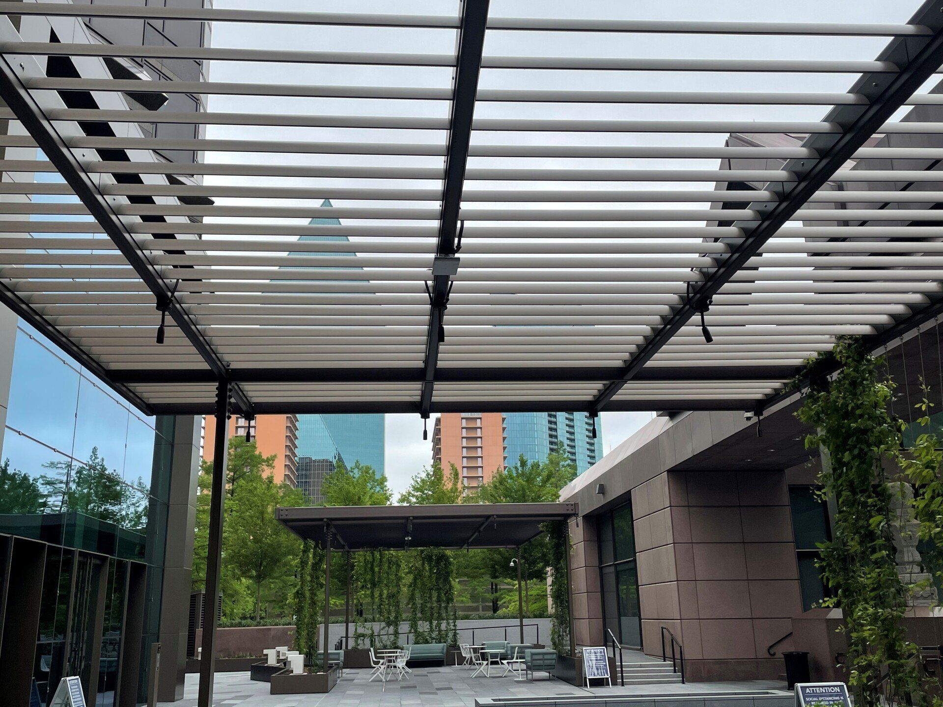 A pergola is sitting on top of a patio in front of a building.