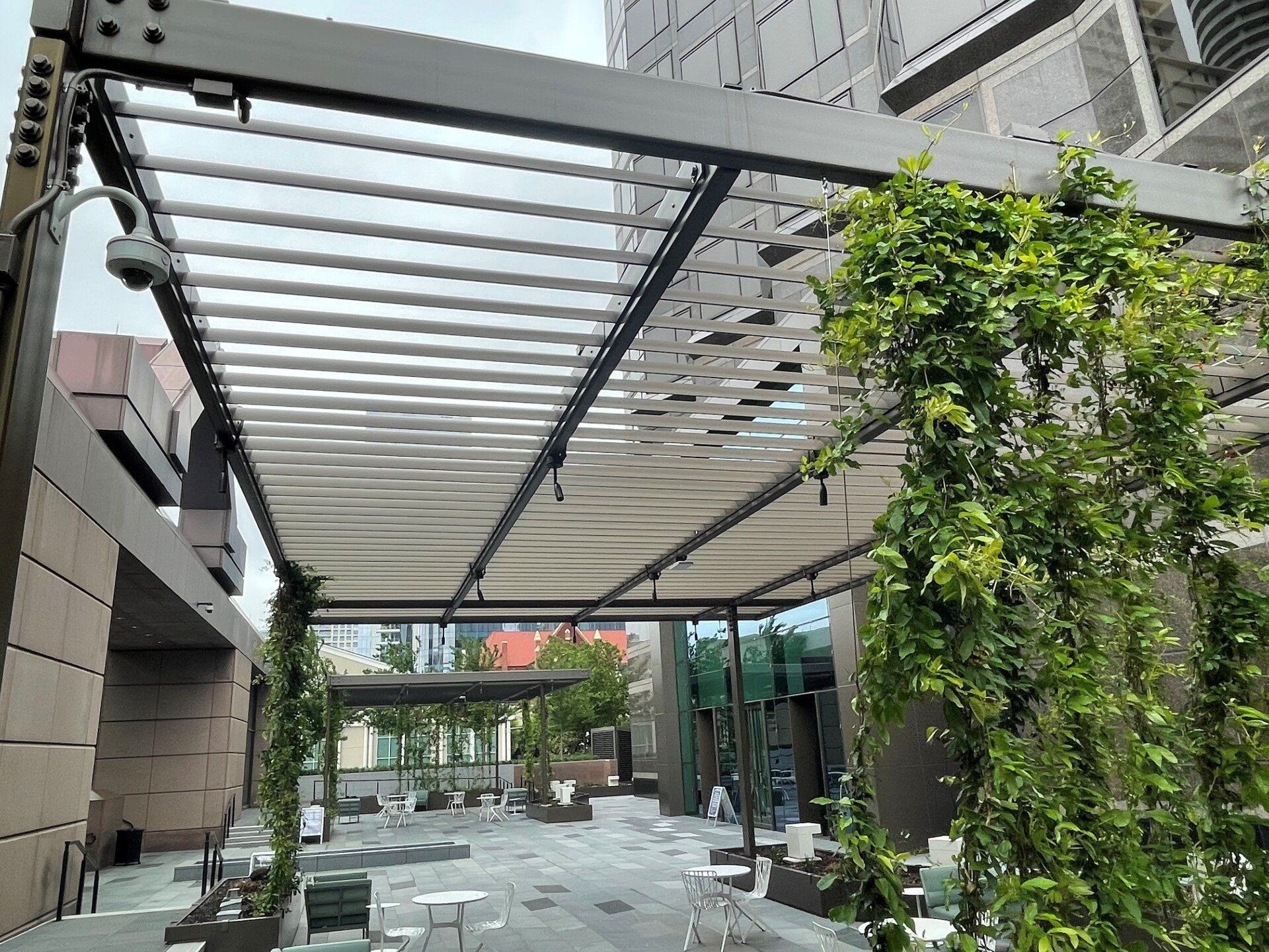 There is a pergola with tables and chairs underneath it.