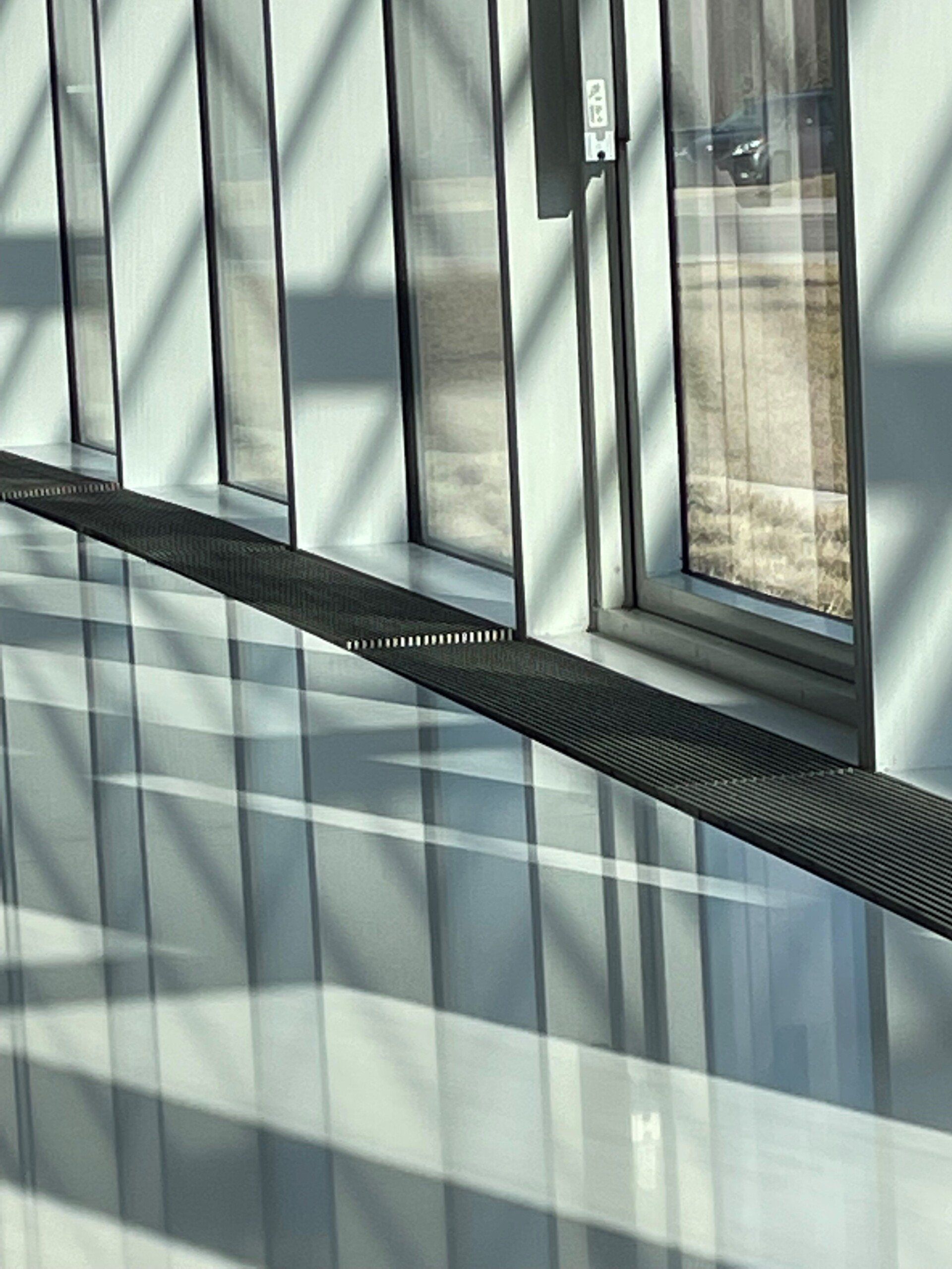 A hallway with a reflection of a car in the windows