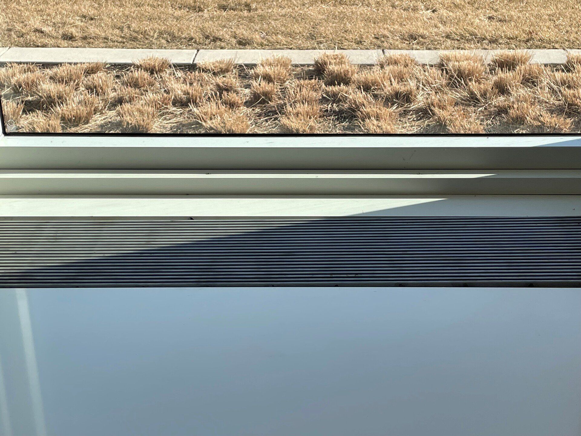 A window with a view of a field of dry grass.