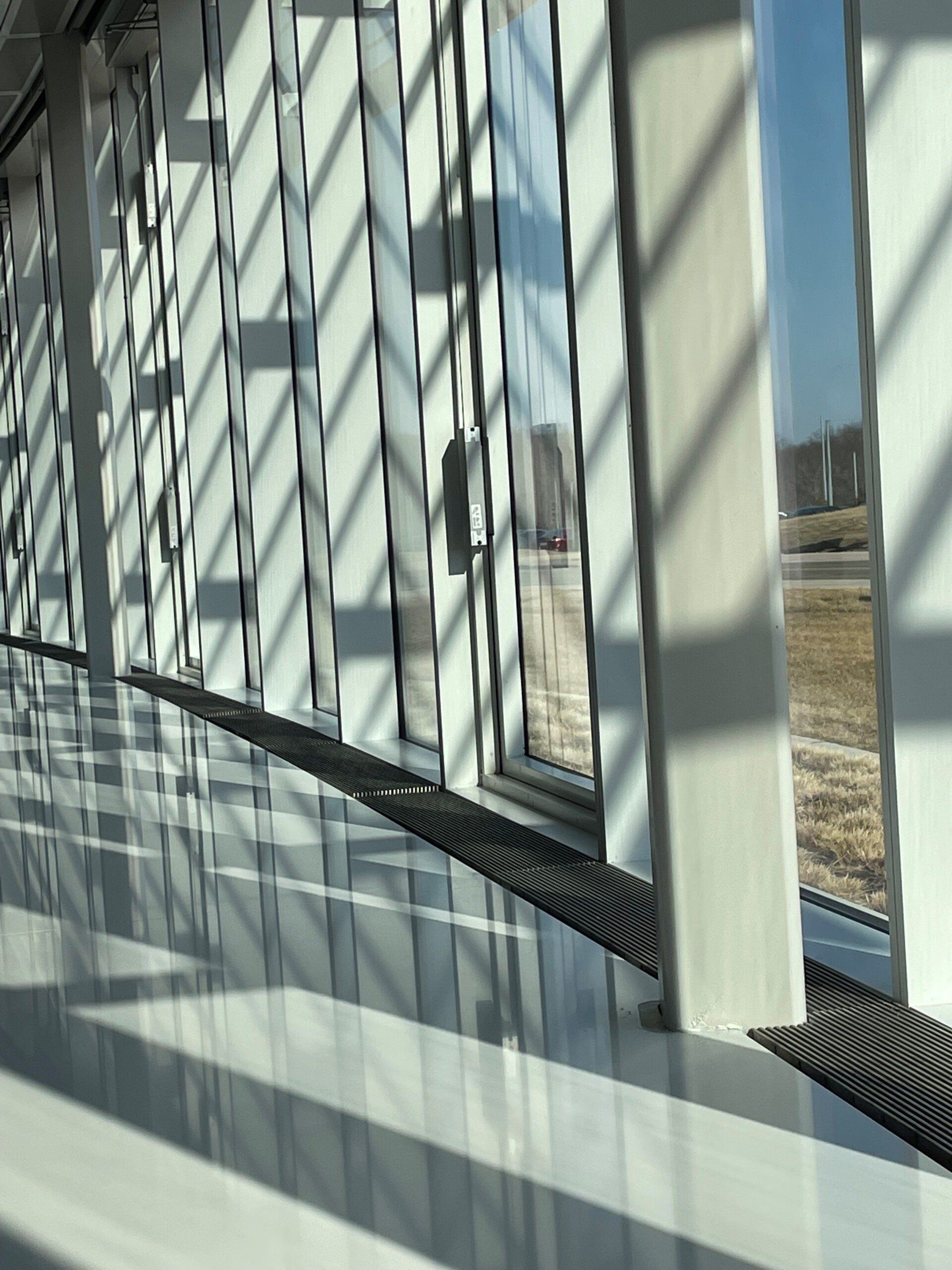 A hallway with a lot of windows and shadows on the floor