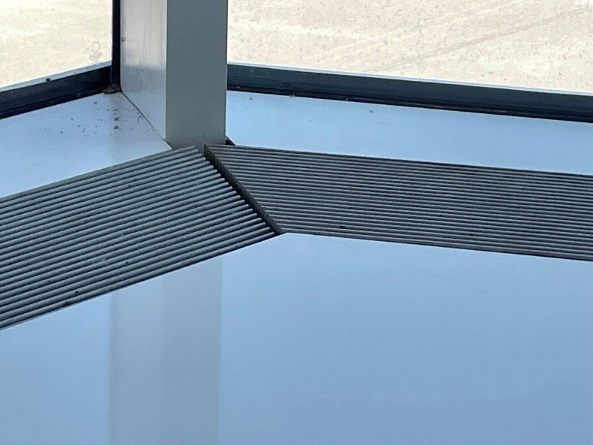 A corner of a room with a window and a rug on the floor.