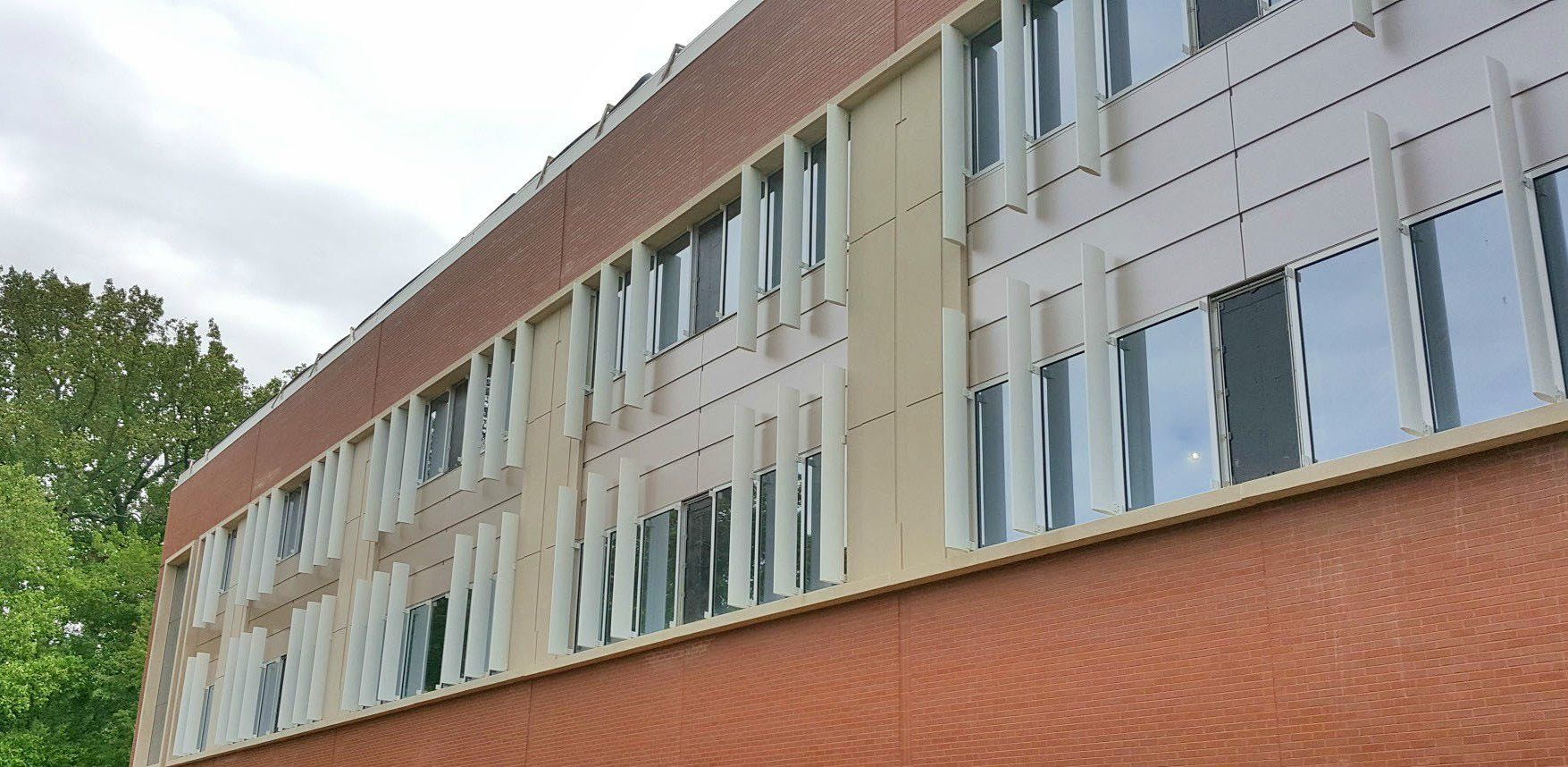 A large brick building with a lot of windows and trees in the background.