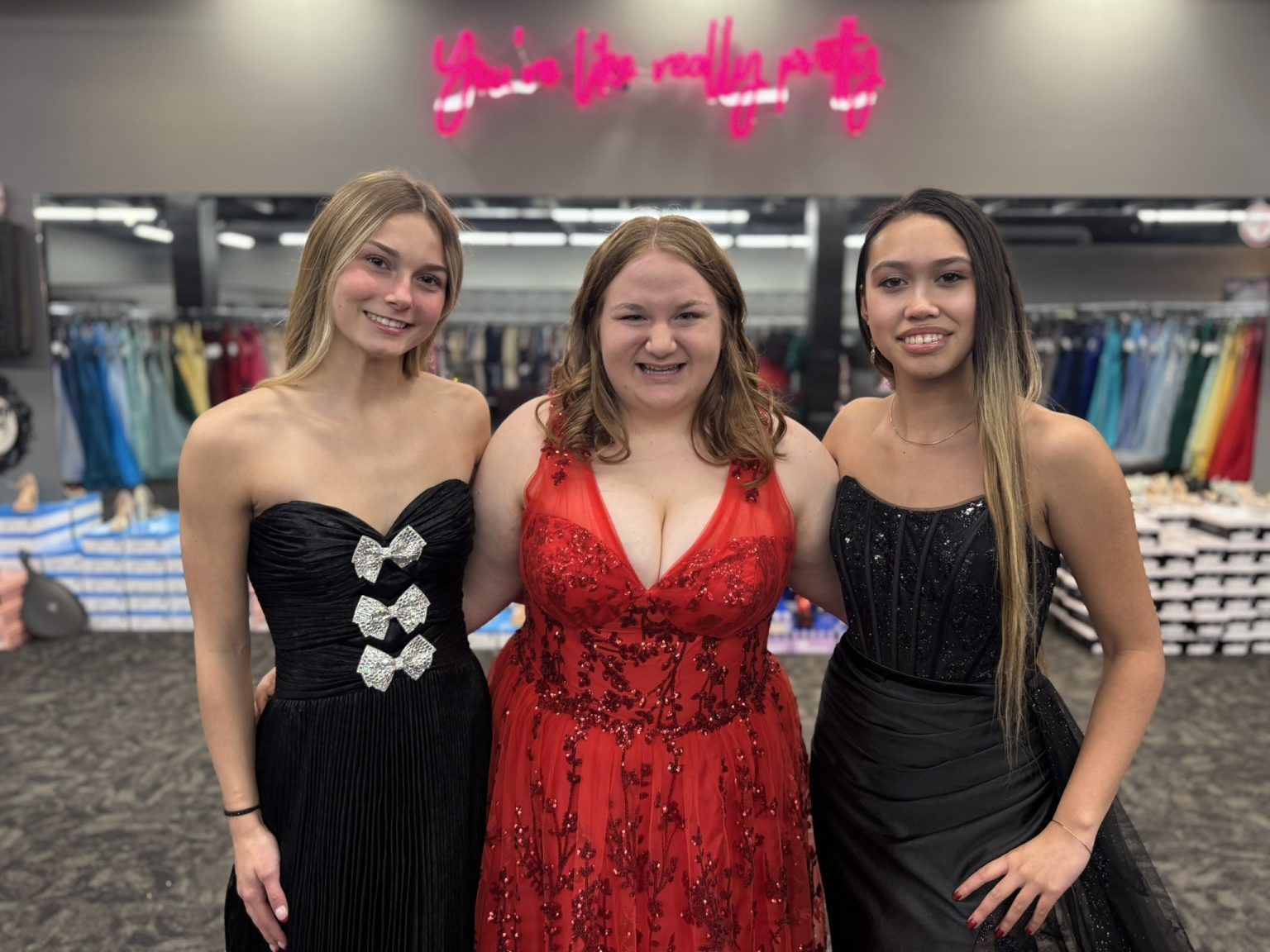 Woman in a white off-shoulder wedding dress smiles in a bridal shop.