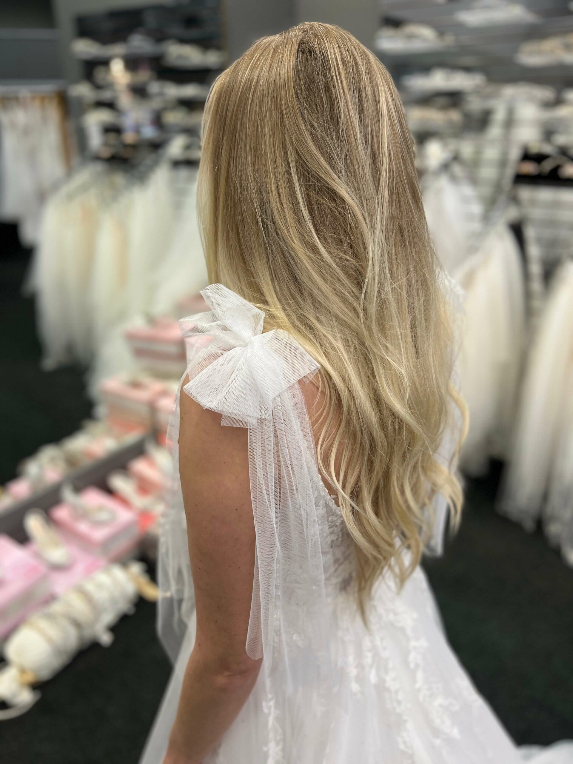 Woman in a white wedding dress with crimped blonde hair, in a bridal shop.