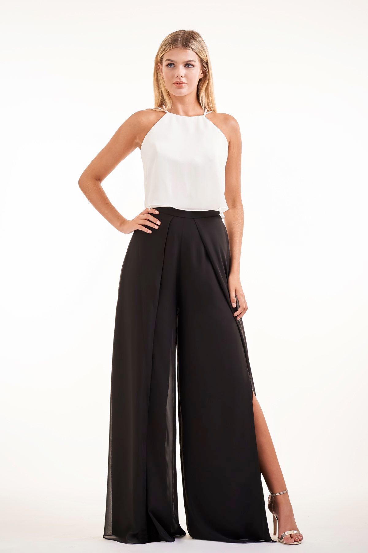Woman wearing a white halter top and black wide-leg pants with a side slit.